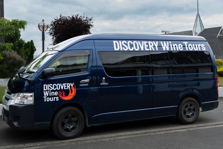 Blue van labeled 'DISCOVERY Wine Tours' parked on a street.