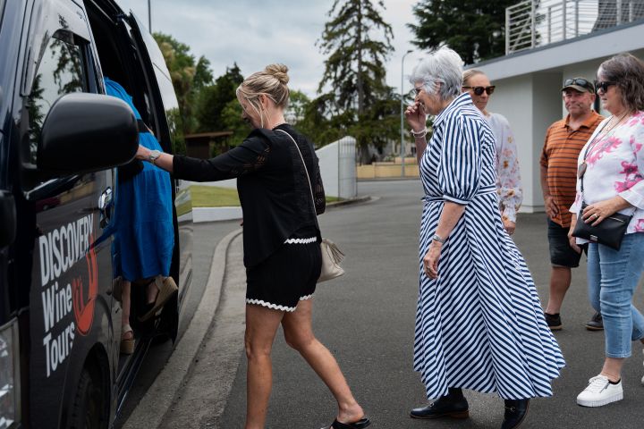 People boarding a Discovery Wine Tours van in a parking lot.